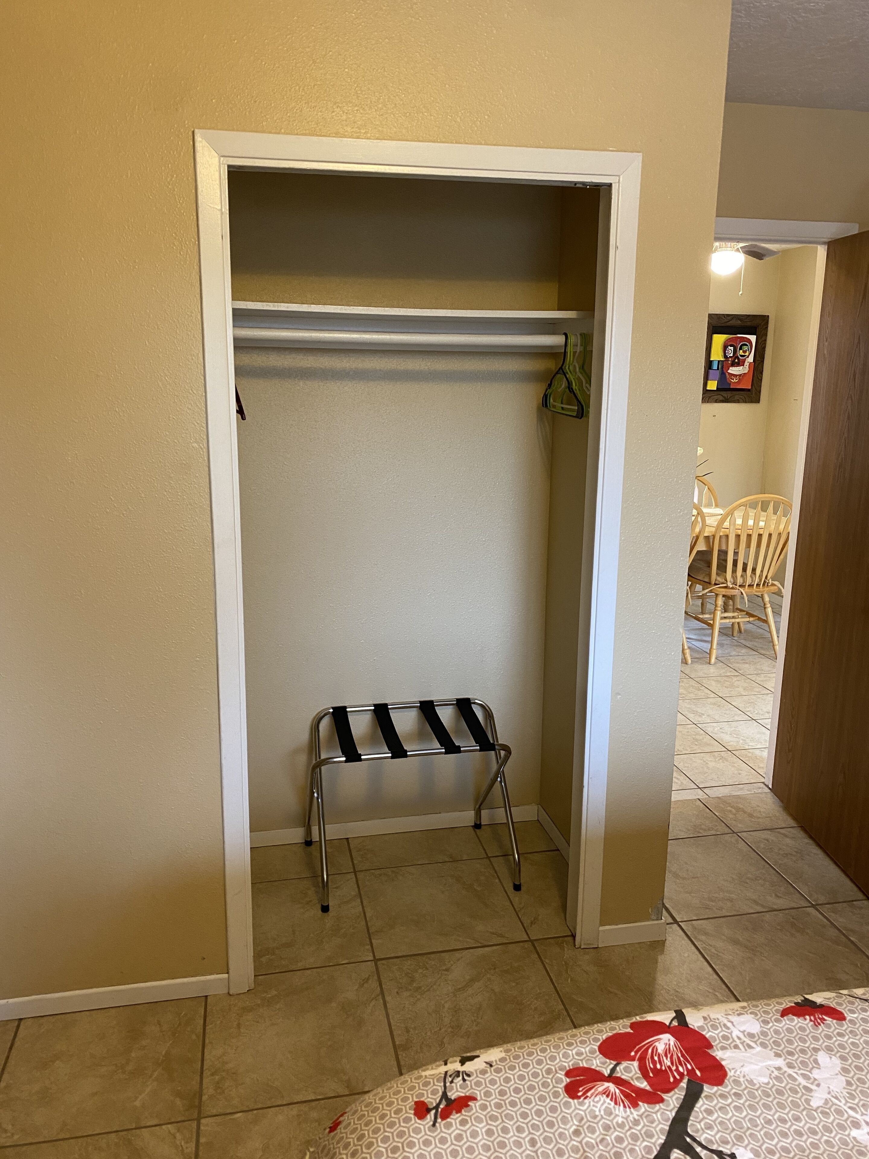 A small, enclosed closet with a metal drying rack and a single hanger.