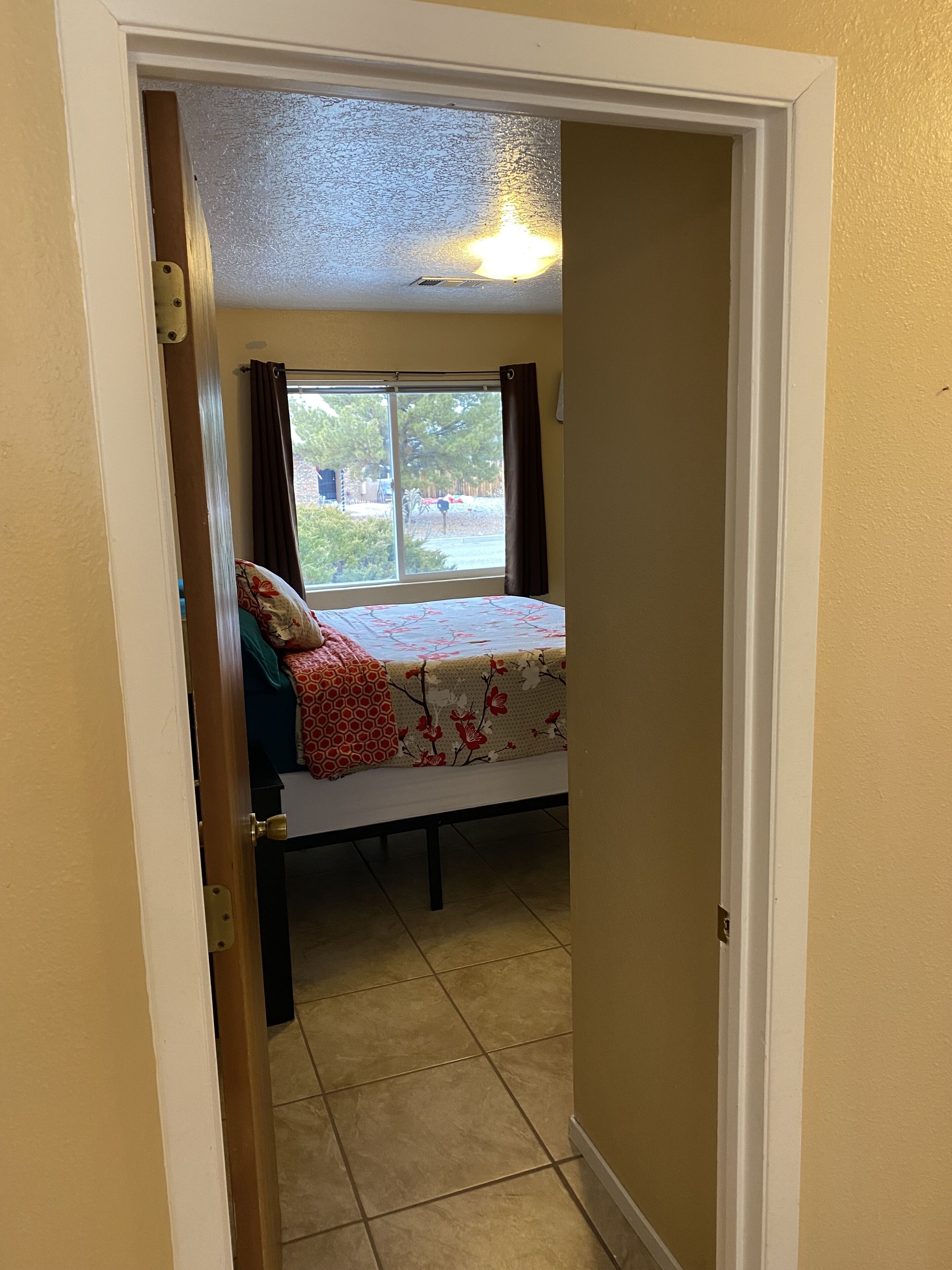 Une chambre à coucher avec un lit, une fenêtre et un luminaire au plafond.