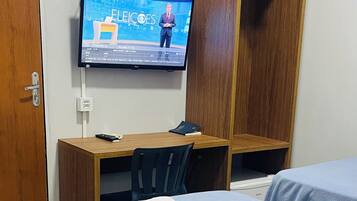 Habitación de hotel con cama, escritorio con computadora, televisor montado en la pared y armario.