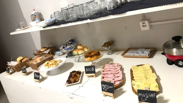 A buffet with various food items and a selection of glasses on a shelf. - Ágape Hotel (Rio Verde)