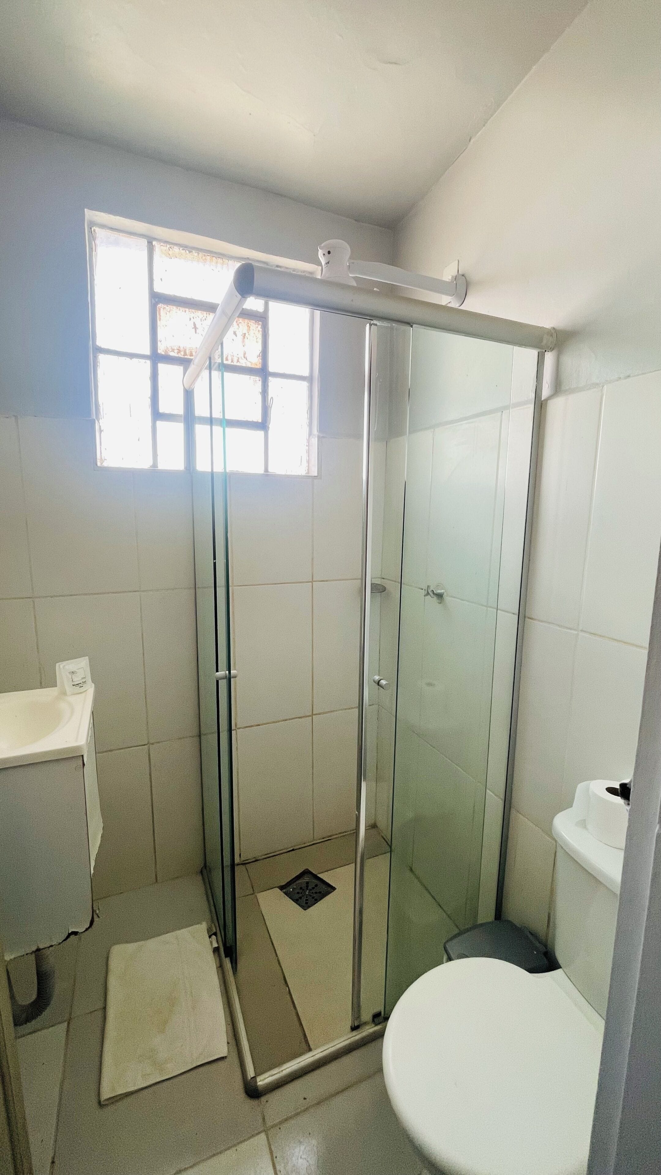 Un baño con ducha de vidrio, inodoro y lavamanos.