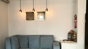 A grey sofa with three black pendant lights and two framed artworks on the wall. - Ágape Hotel (Rio Verde)