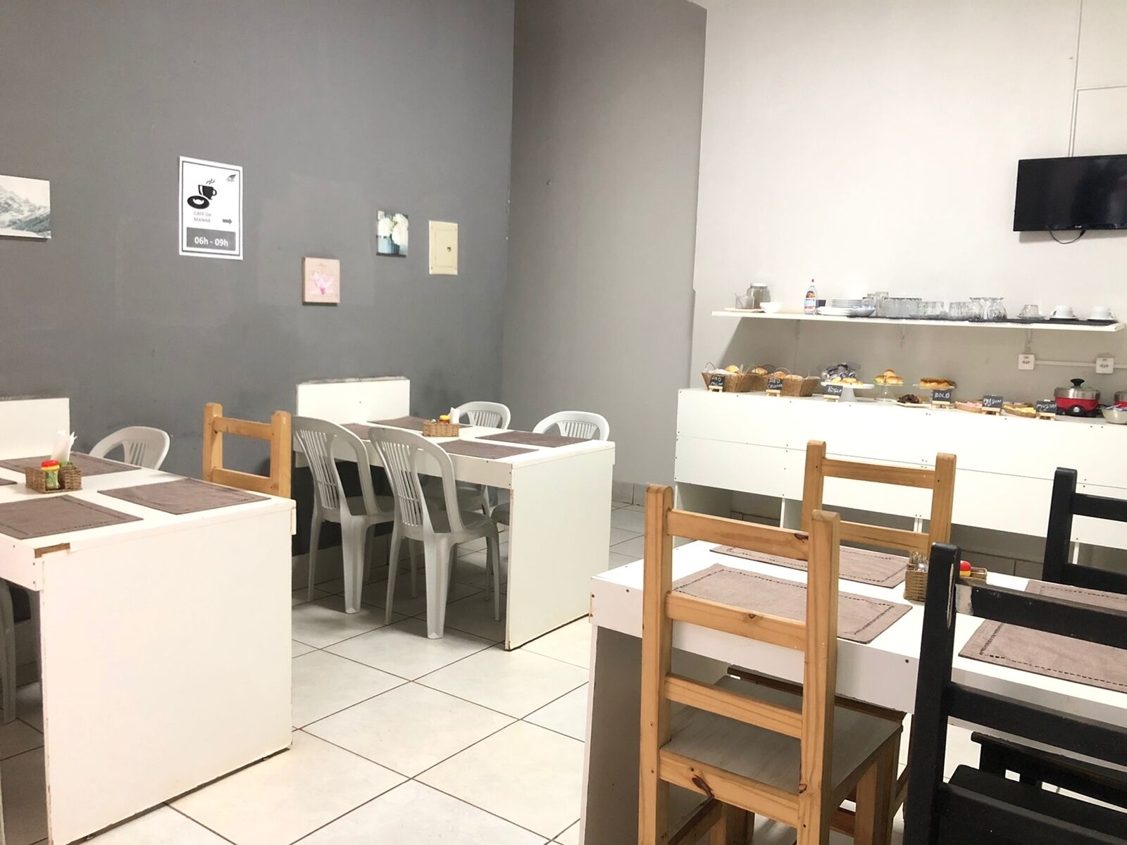 Un café avec un comptoir et des chaises, un sol carrelé et un mur orné d’une enseigne représentant une tasse de café.