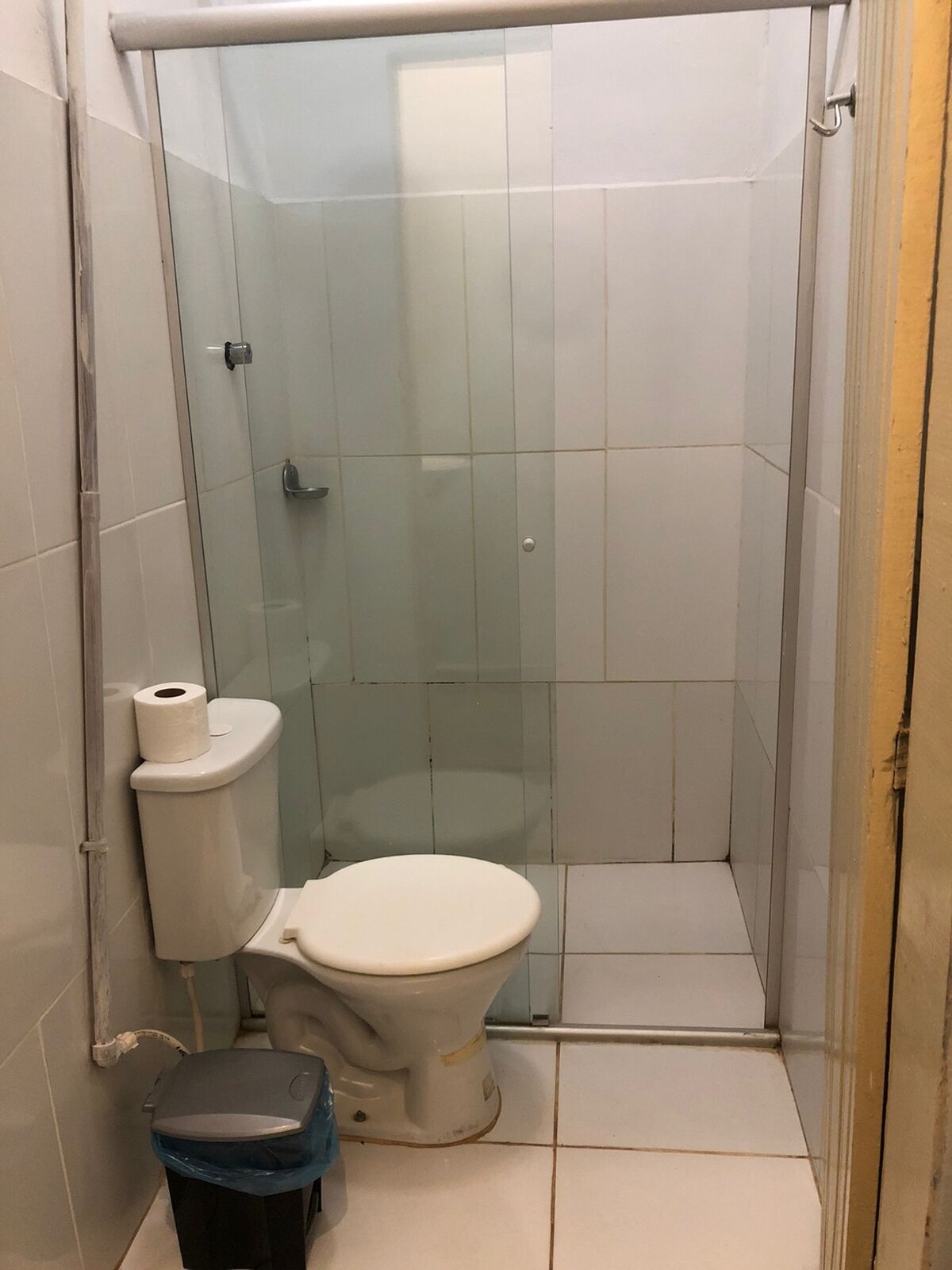 Casa de banho pequena e fechada, com sanita, um cesto de lixo e zona de duche.