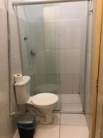 Casa de banho pequena e fechada, com sanita, um cesto de lixo e zona de duche.