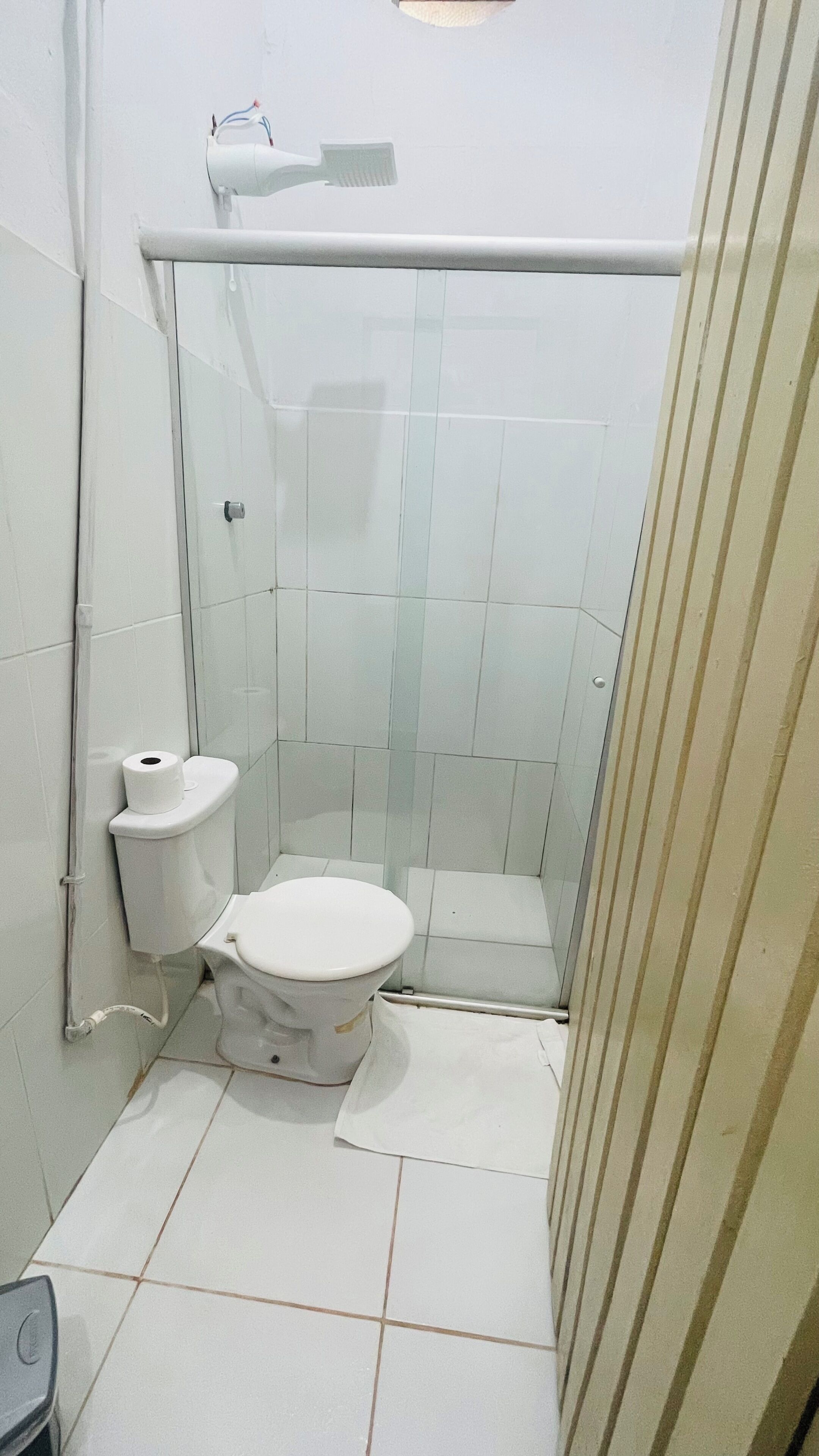 Ein kleines, abgeschlossenes Badezimmer mit Toilette, Duschbereich und Handtuchhalter.