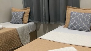 A hotel room with two beds, each with a patterned bedspread and matching pillows. A rolled-up white towel is placed on the floor. - Ágape Hotel (Rio Verde)