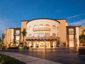 A hotel with a curved facade, multiple balconies, and a paved entrance area. - Villa LA Estancia LOS Cabos (CABO SAN LUCAS)