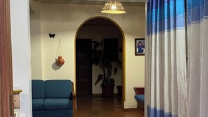 Un pasillo con un sofá azul, una planta en maceta y una lámpara colgante.
