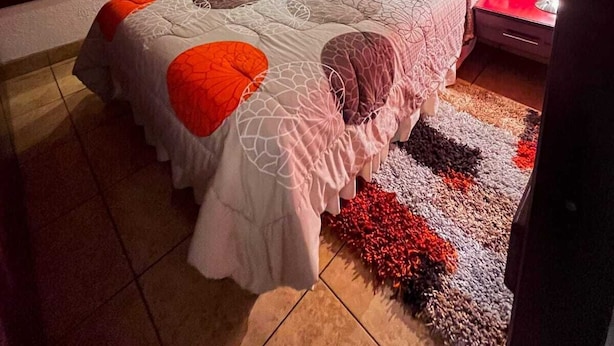 Un dormitorio moderno con una cama grande, una pared de acento roja y fotografías enmarcadas.