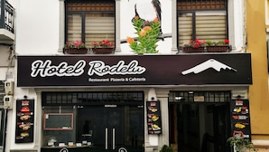 Un edificio con un letrero que indica Hotel Rodelu, que presenta un logo de montaña.
