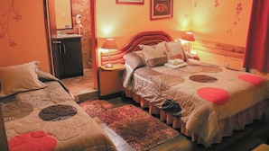 Un dormitorio con dos camas, una mesita de noche con lámpara, un espejo y una pequeña mesa con teléfono.