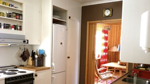 Een kleine keuken met witte kastjes, een koelkast, een fornuis en een spoelbak.