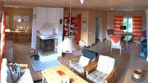 Een gezellig chaletinterieur met een open haard, houten meubels en een eethoek.