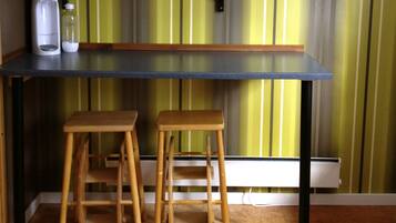 A kitchen with a black countertop, two wooden stools, and a striped rug.