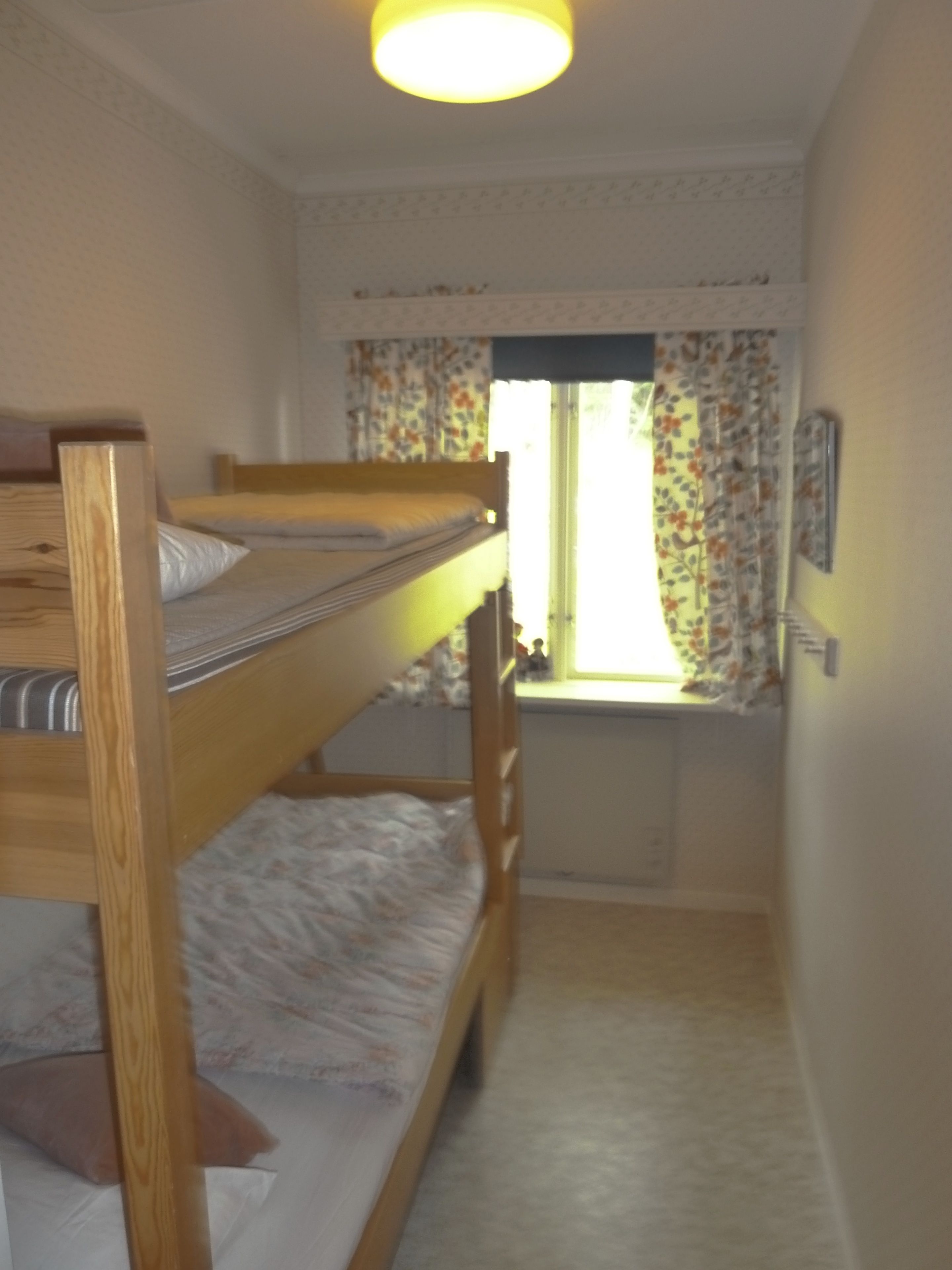 A bunk bed room with a window and curtains.