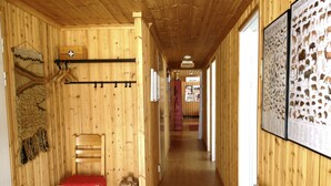 Een houten gang met een houten stoel en een rode deken, een hangende kapstok en lijstwerken met dierenfoto's aan de muur.