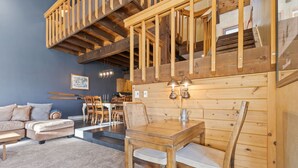 A cozy room with a wooden dining table, cushioned chairs, a sofa, and a staircase leading to an upper level. - Less Than 100 Yards to Slopes + Private Hot Tub w/ Gondola Views (Steamboat Springs)