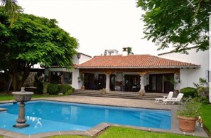 Una casa con piscina, patio cubierto y jardín.