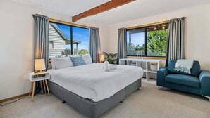 A modern bedroom with a large bed, a desk, and a sofa. - Zenith - Freycinet Holiday Houses (Coles Bay)
