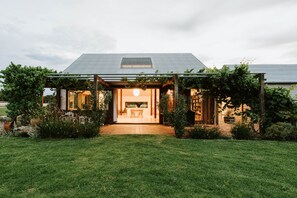 Une maison moderne dotée d’un patio couvert, d’un coin repas et d’un jardin.