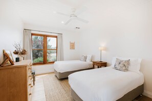A bedroom with two beds, a wooden dresser, a desk, a window with curtains, and a ceiling fan. - Abercorn - one of Stayz’s 2025 Holiday Homes of the Year (Buckaroo)