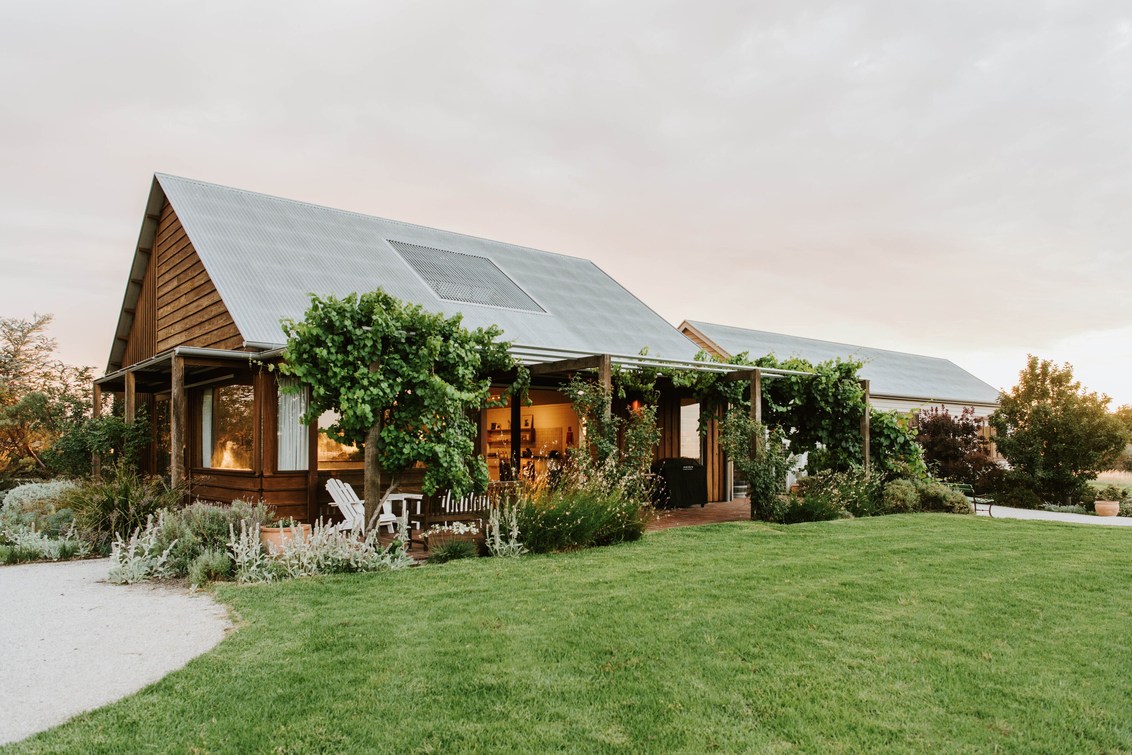 A modern house with a sloped roof, wooden exterior, and a well-maintained lawn.