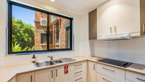 Eine moderne Küche mit Fenster, Spüle aus Edelstahl und weißen Schränken.