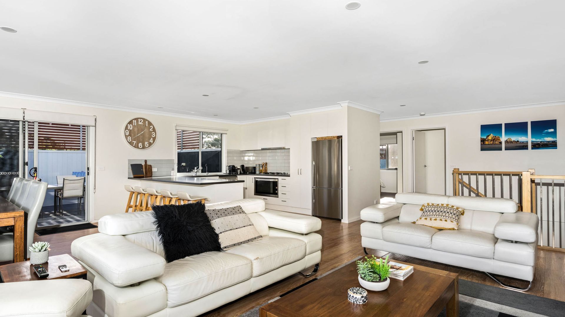 A modern living room with a white sofa, a coffee table, and a dining area with a table and chairs.