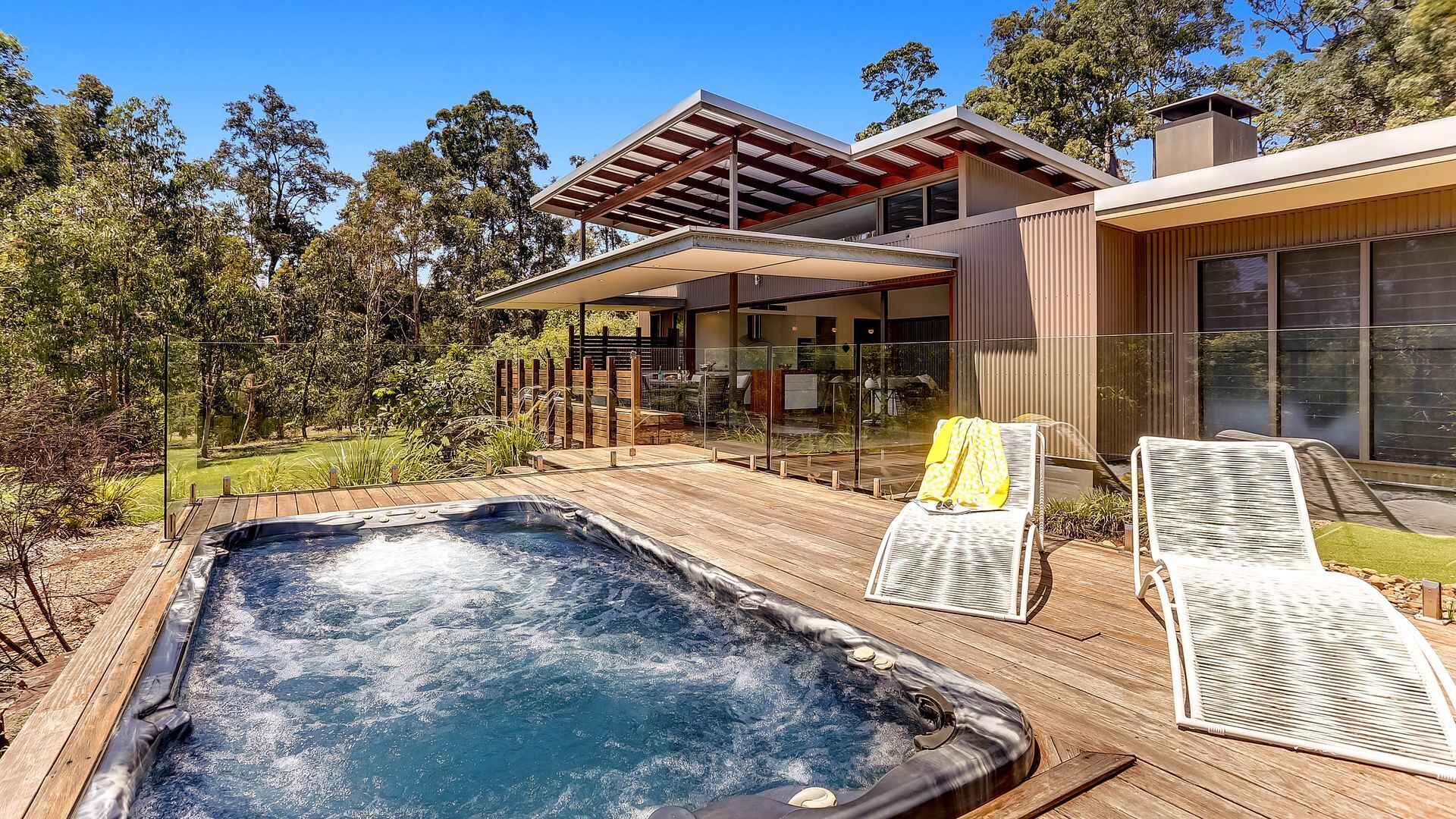 A modern house with a hot tub, outdoor seating, and a garden.
