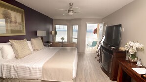 Una habitación de hotel con una cama grande, televisión, escritorio y vista al mar.