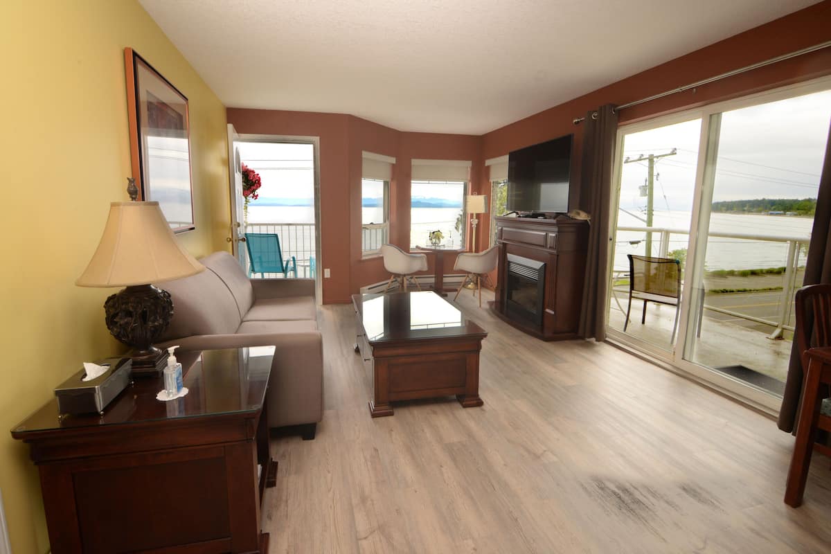 A living room with a sofa, a coffee table, a TV, and a view of the water.
