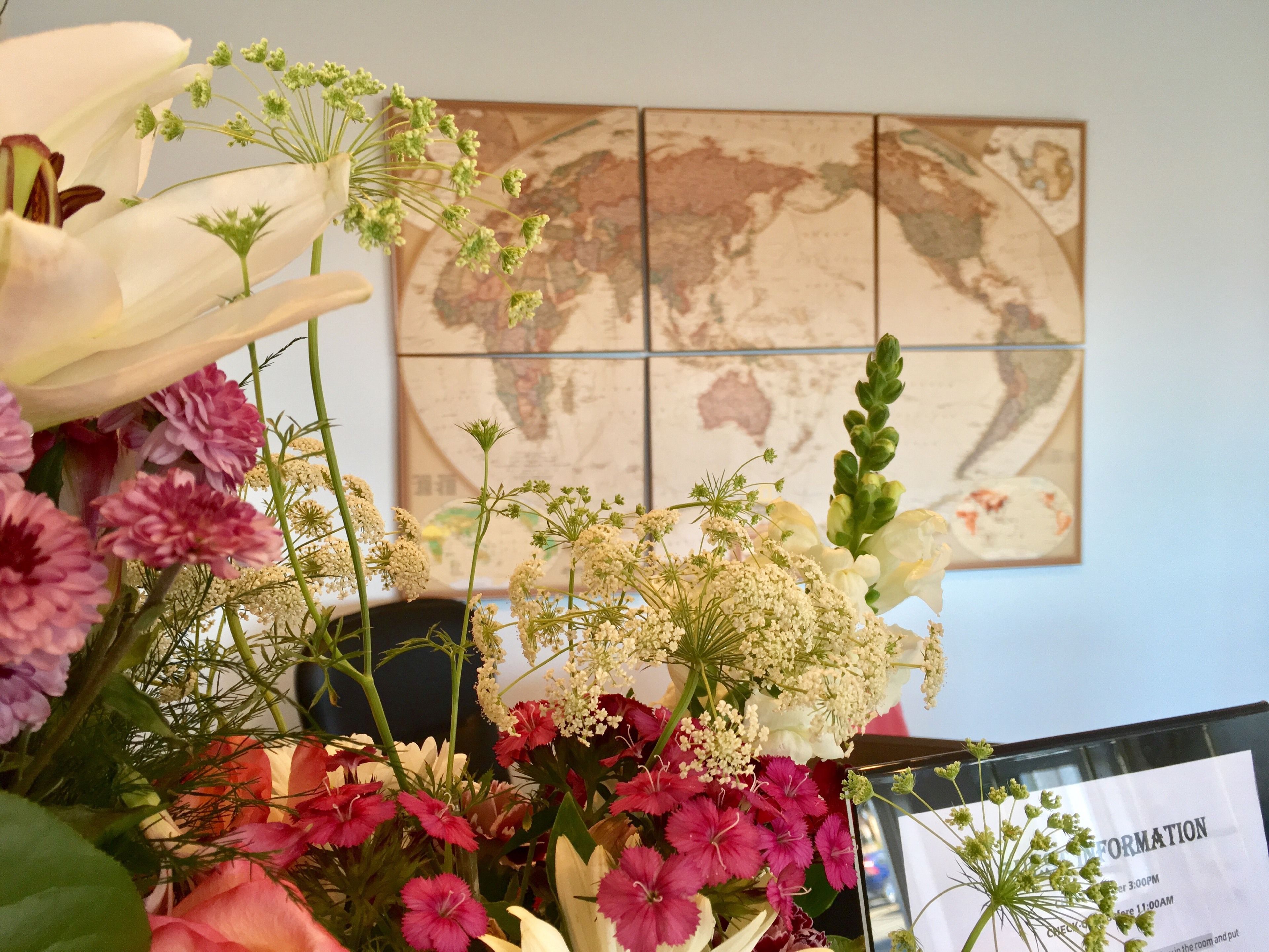Um arranjo floral em frente a um mapa-múndi na parede.