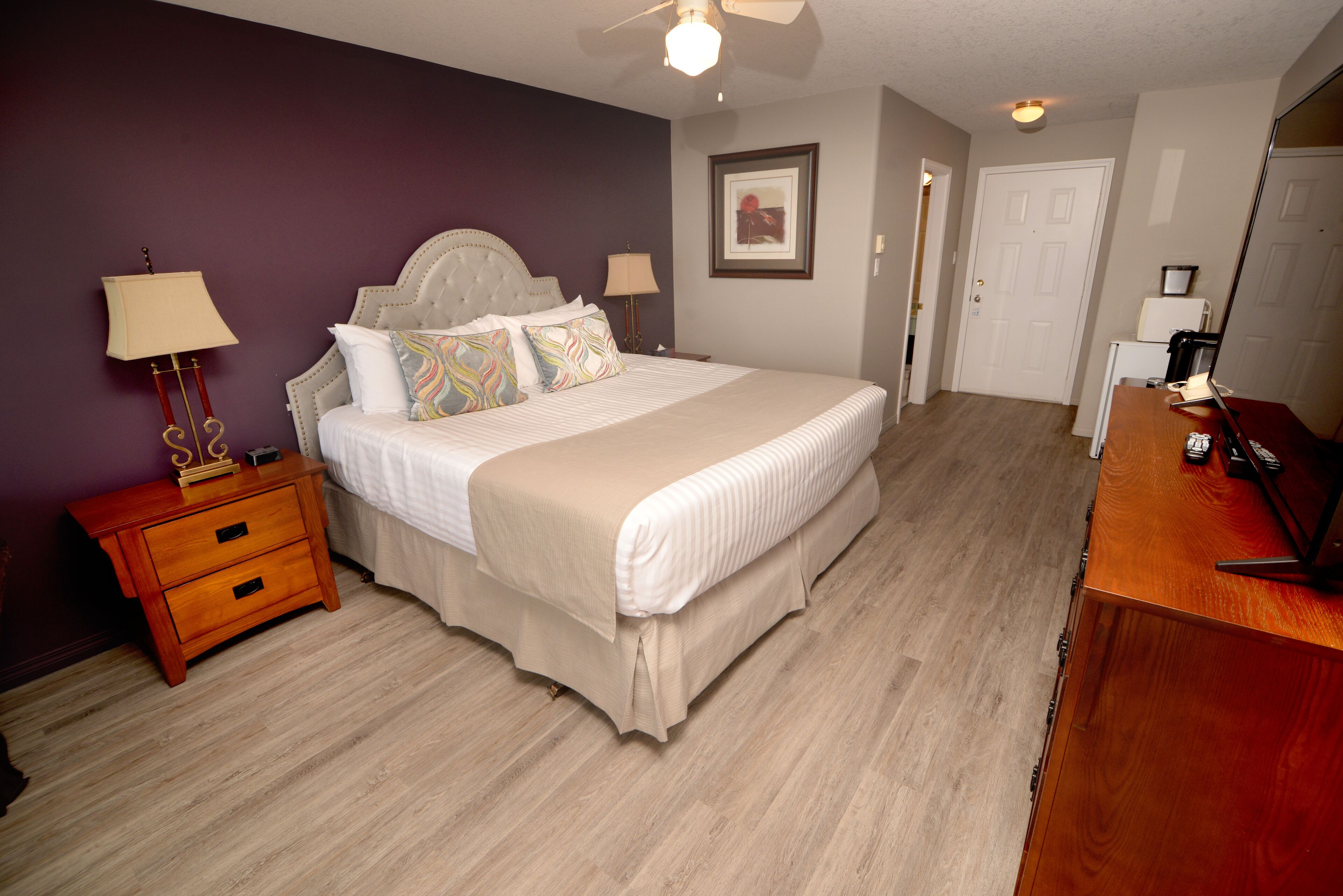 A neatly arranged bedroom with a bed, bedside tables, and a dresser.