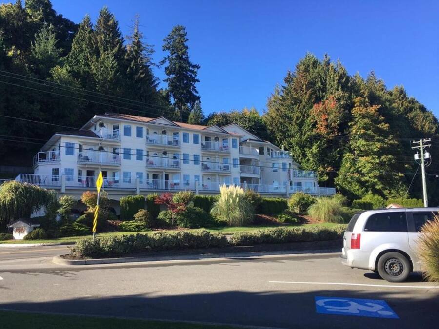 Ein mehrstöckiges Hotel mit Balkonen, umgeben von Bäumen und einem Parkplatz.