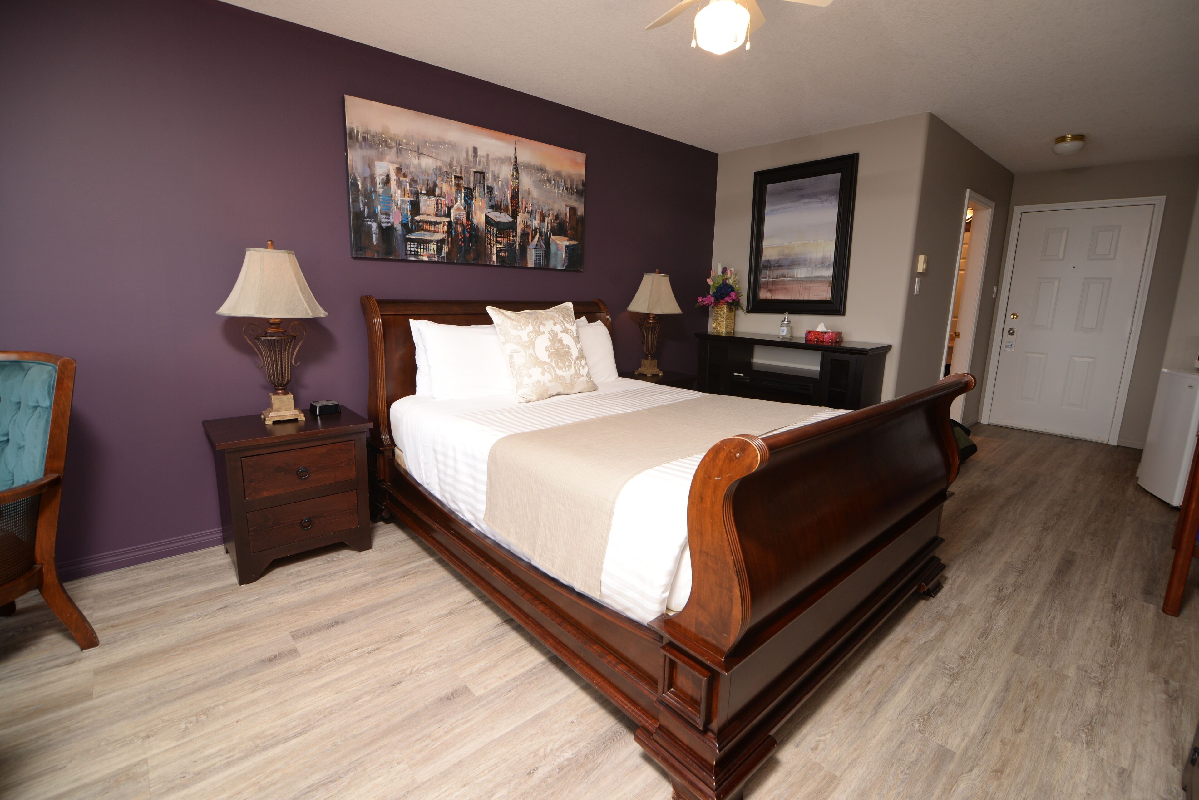 A bedroom with a wooden bed, two nightstands with lamps, a dresser, and a door.