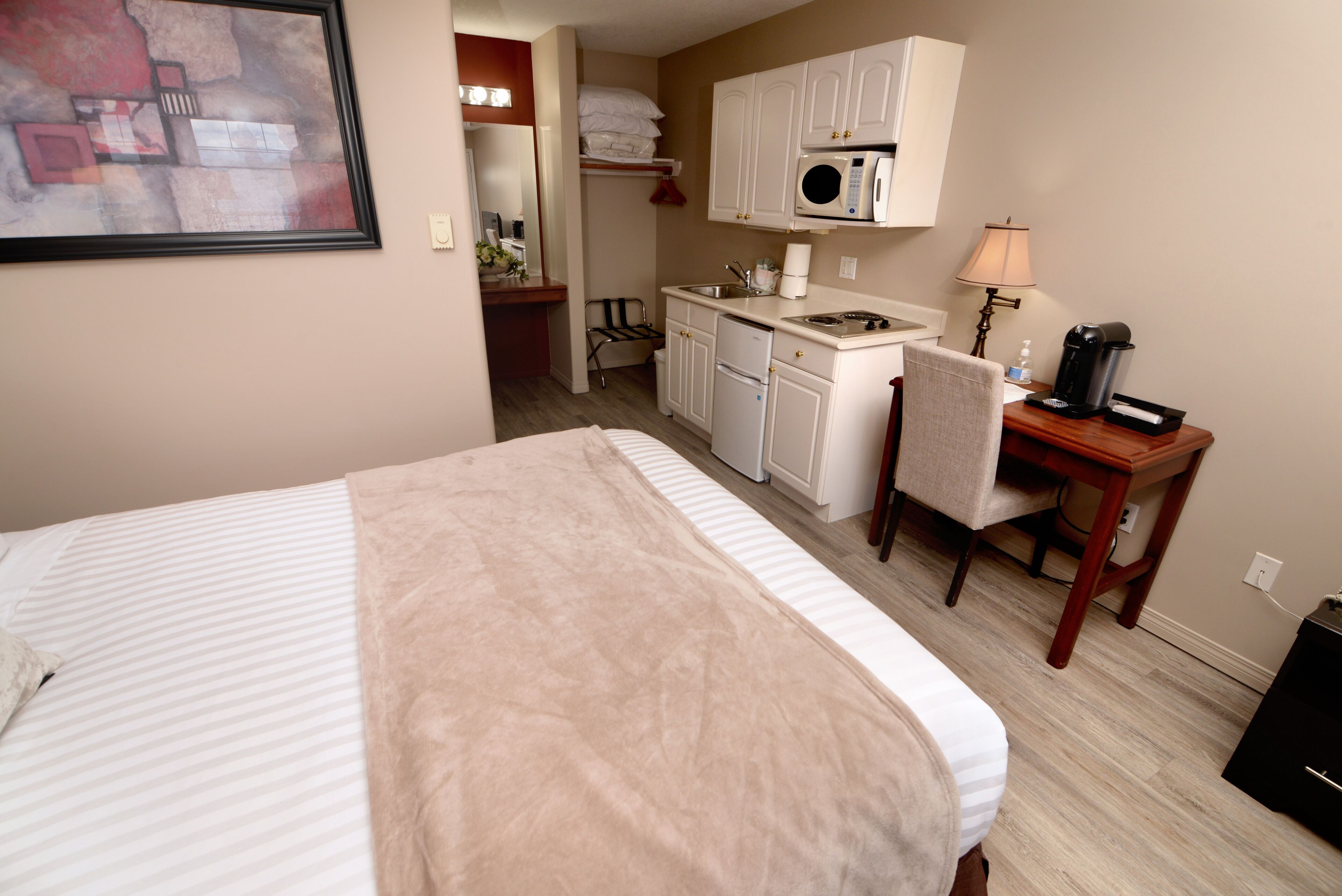 Habitación de hotel con cama, escritorio, kitchenette y baño.