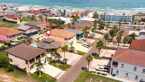 A coastal residential area with a mix of single and multi-story buildings, some with balconies and a few with visible swimming pools. - The Octagon at Capricorn (South Padre Island)