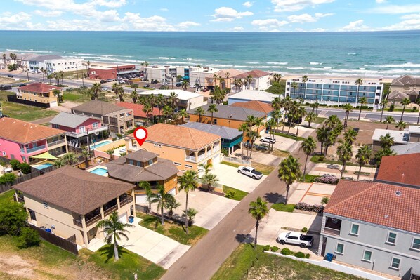 A coastal residential area with a mix of single and multi-story buildings, some with balconies and a few with visible swimming pools.
