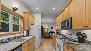 A kitchen with wooden cabinets, granite countertops, a refrigerator, a microwave, and a stove. - Resort Condo with Poker Table, 6 Beds and 1 dog permitted! (Whittier)
