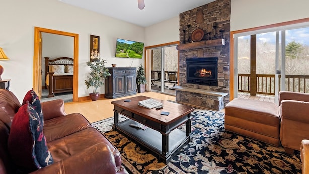 A living room with a fireplace, a ceiling fan, and a large window overlooking a deck. - Resort Condo with Poker Table, 6 Beds and 1 dog permitted! (Whittier)