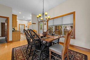 A dining area with a wooden table, black chairs, and a chandelier.