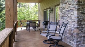 A wooden deck with outdoor furniture, including chairs and a table, and a stone wall. - Resort Condo with Poker Table, 6 Beds and 1 dog permitted! (Whittier)