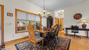 A dining room with a wooden table, chairs, a chandelier, and a large clock on the wall. - Resort Condo with Poker Table, 6 Beds and 1 dog permitted! (Whittier)