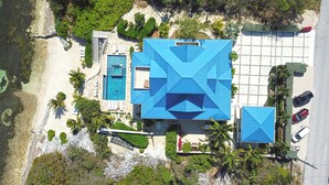 Eine Vogelperspektive eines Resorts mit einem großen Pool, einem separaten Gebäude mit blauem Dach und einem Parkplatz.