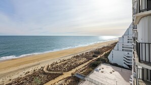 Un hôtel situé en bord de mer, offrant une vue sur l’océan, une plage de sable et un espace paysager agrémenté de sentiers.
