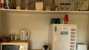 A kitchen with a microwave, toaster, and refrigerator. There are jars on the shelf and a basket with a sign. - Private , tranquil cosy retreat with massage chair-l (Melbourne)