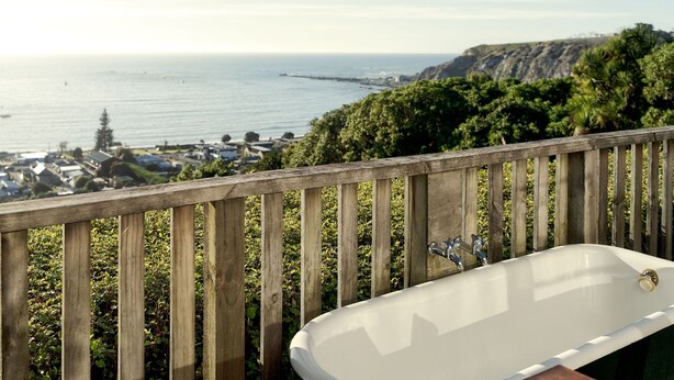 Una bañera con vista al océano y una terraza de madera.