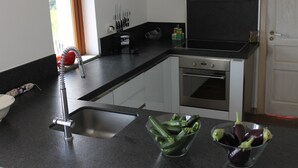 A modern kitchen with a black countertop, stainless steel appliances, and a clear glass bowl containing vegetables. - Lovely greenery detached house with inground private swimming pool.  Large garde (Tresana)