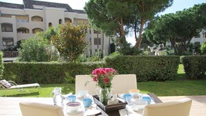 Un área de comedor al aire libre con una mesa dispuesta para cuatro personas, rodeada de sillas.